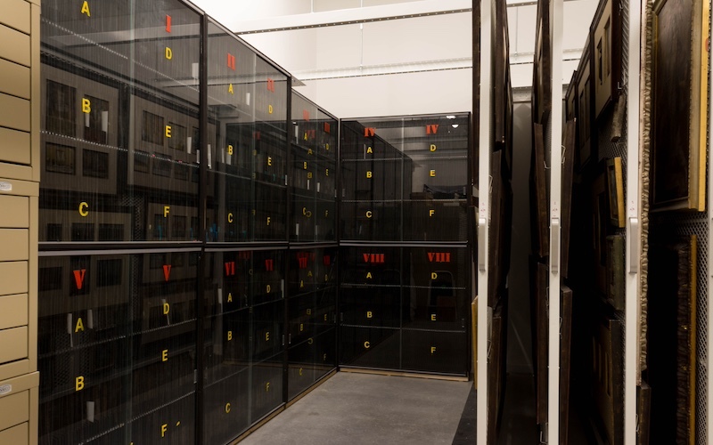 Room filled with shelves behind black tinted glass with yellow numbers on each storage cabinet bin