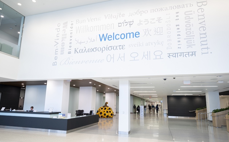 Reception desk in lobby with Pumpkin behind it and the word welcome written in different languages on the wall above the desk